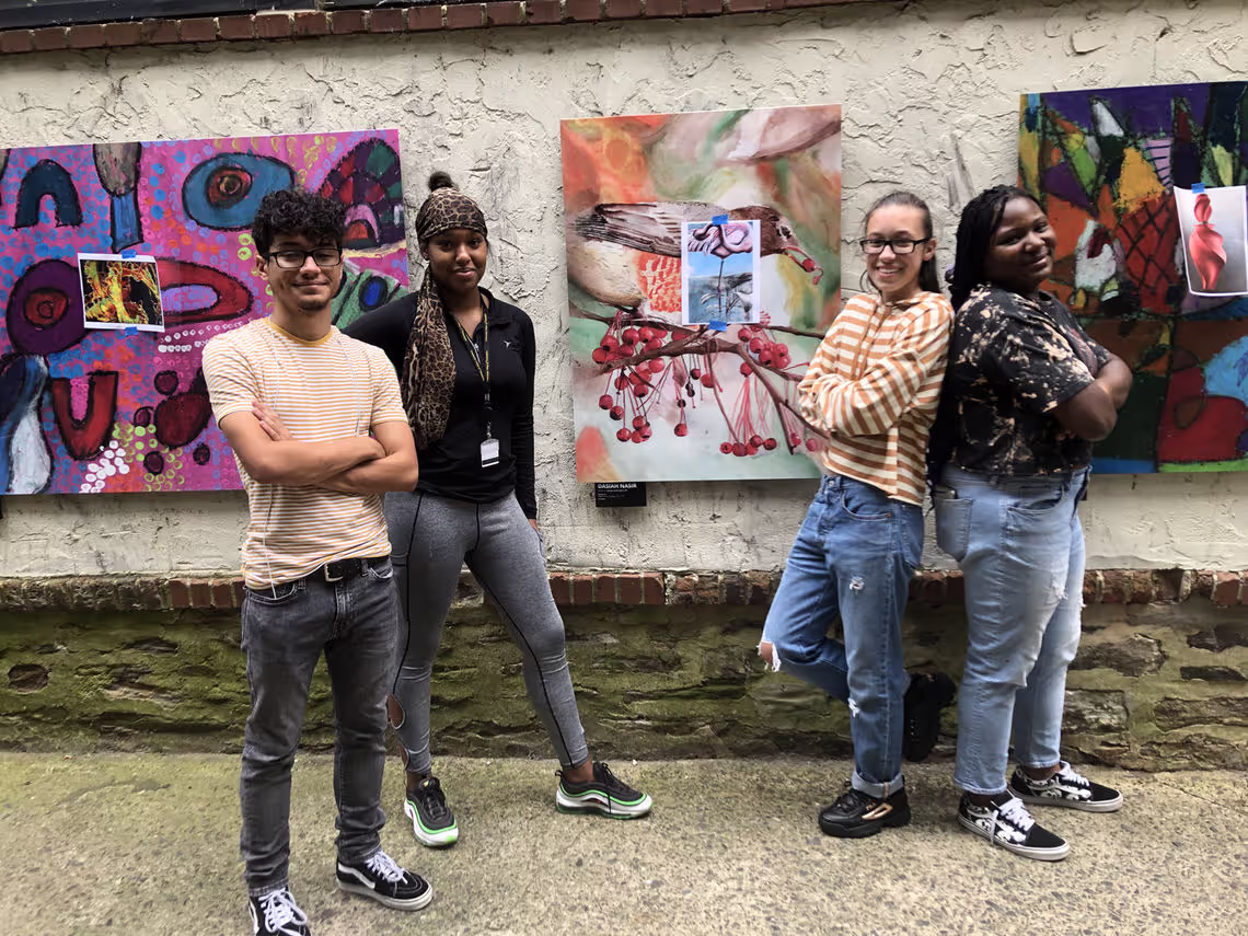 A group of people standing next to each other in front of paintings